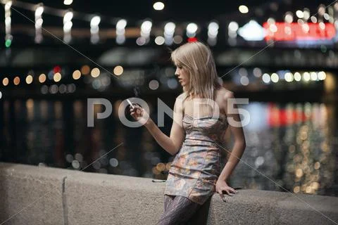 Caucasian woman smoking cigarette on urban bridge Stock Photos