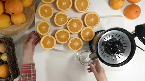 Caucasian woman squeezing oranges using electric juicer.  Video stock 125540323