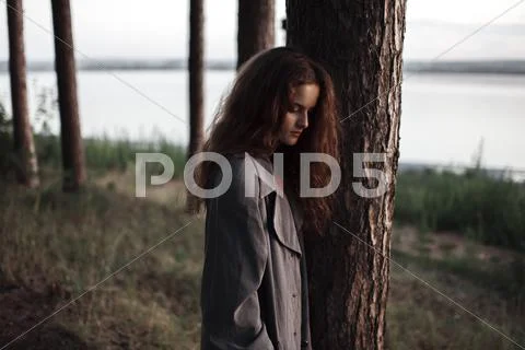 Caucasian woman standing behind tree near rural river Stock Photos