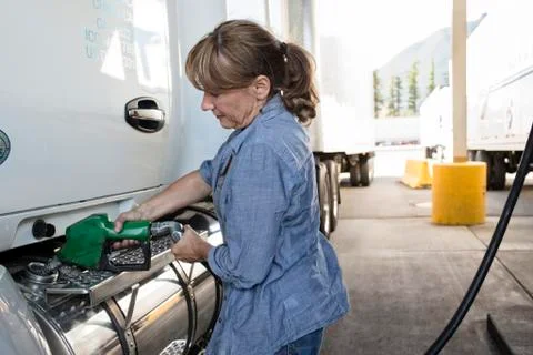 Caucasian woman truck driver filling truck with diesel fuel at a truck stop. Stock Photos