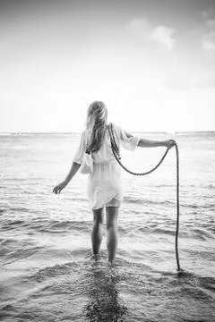 Caucasian woman wading in ocean waves holding rope Stock Photos