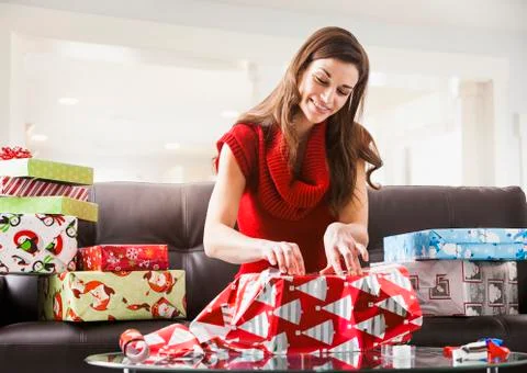 Caucasian woman wrapping Christmas presents in living room Stock Photos