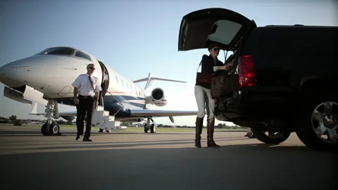 Caucasian women and pilot boarding private jet from car on tarmac Stock Footage