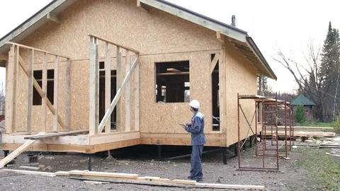 Caucasian worker in front of a house. Architect or builder check plans in a half Stock Footage 96902252