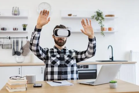Caucasian worker testing VR headset while sitting at wooden table. 스톡 사진