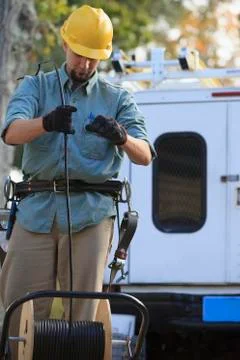 Caucasian worker unrolling cable spool 库存照片