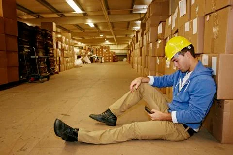 Caucasian worker using cell phone in warehouse Stock Photos