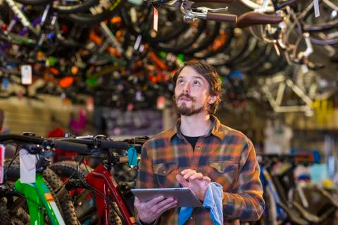 Caucasian worker using digital tablet in bicycle shop Stockfoto's