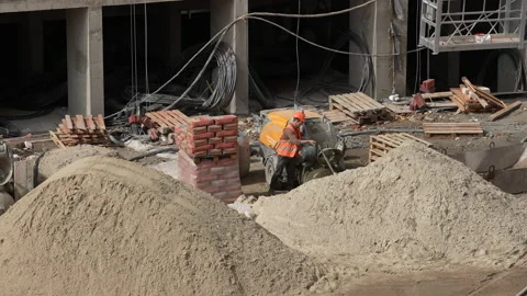Caucasian  workers in helmets uniforms draws water into a bucket to mix cement Stock Footage 172264211
