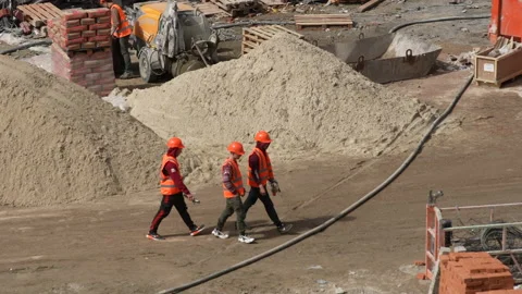 Caucasian workers in helmets uniforms, group of builders walk construction site Stock Footage 172261550