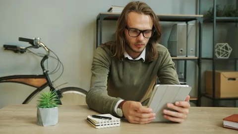 Caucasian young business man with glasses working on the tablet on the new Stock Footage