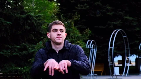 Caucasian young guy in a black jacket walks in the park and talks to the camera Stock Footage 129688436