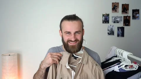 Caucasian young Guy is looking into the mirror choosing a shirt Stock Footage 147900246