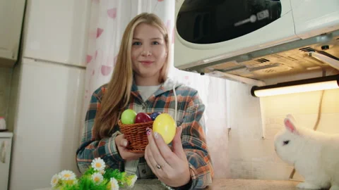 Caucasian young looking at the camera woman in plaid shirt takes an Easter egg Video stock 330491253