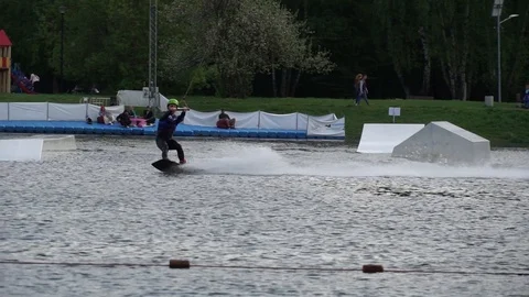 Caucasian young man doing tricks on wakeboard in the city lake Stock Footage 112687375