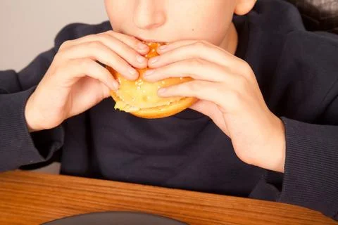 Caucasian young man eats half-eaten sesame fresh hamburger Foto stock
