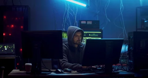 Caucasian young man hacker commiting cybercrime while hacking at two computers Video stock 124338019