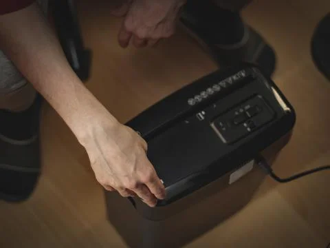 Caucasian young man is pressing the button to destroy important documents in  Stock Photos