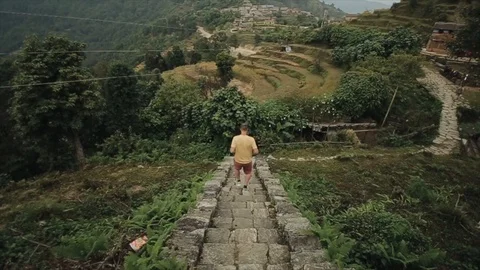 A caucasian young man running down nepalese stairs, trek. Landscape, terraced 库存影片 126750585
