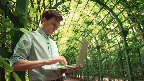 Caucasian young man using laptop standing at city park. Summer day Video stock 77169085