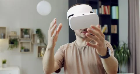 Caucasian young man in VR headset standing in room and having virtual reality Stock Footage 220369716