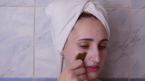 Caucasian young model without makeup, doing a facial massage using a Gua Sha sto Stock Footage 180496546