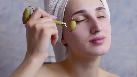 Caucasian young model without makeup, doing a facial massage using a Gua Sha sto 스톡 동영상 180499336