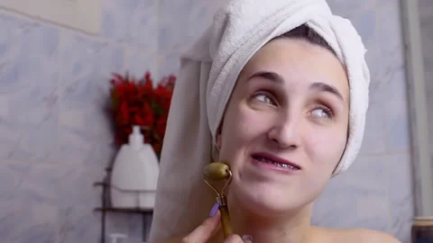 Caucasian young model without makeup, doing a facial massage using a Gua Sha sto Stock Footage 180499509