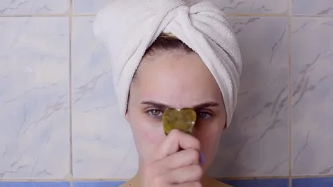 Caucasian young model without makeup, doing a facial massage using a Gua Sha sto Stock Footage 180499963