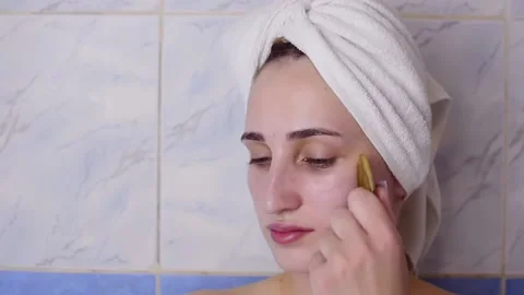 Caucasian young model without makeup, doing a facial massage using a Gua Sha sto Stock Footage 180499971