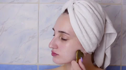 Caucasian young model without makeup, doing a facial massage using a Gua Sha sto Stock Footage 180500001