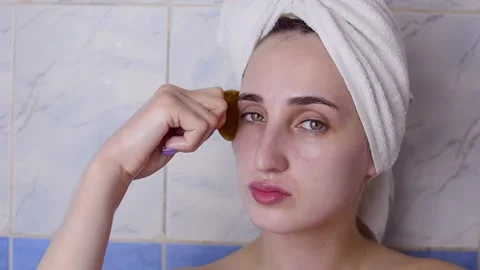 Caucasian young model without makeup, doing a facial massage using a Gua Sha sto Stock Footage 180500120