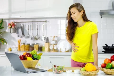 Caucasian young pregnant painful female mother in casual outfit standing ho.. Stock Photos