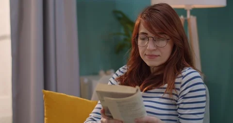 Caucasian young pretty red-haired woman in glasses reading an interesting story Stock Footage 122497907