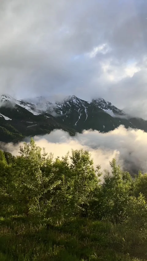 Caucasus mountain range of snow-capped peaks in clouds and setting sun Stock Footage 278004085