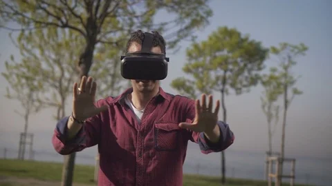 Caucation male experiencing VR technology on a sunny day outside Stock Footage 80946442
