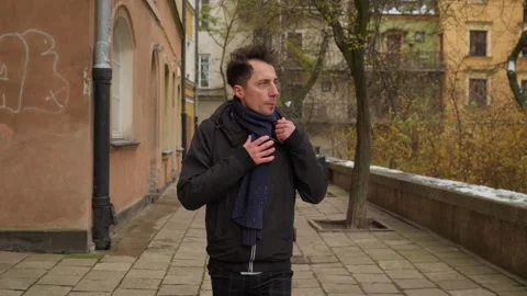 Caught in the cold, a man wraps his scarf tighter, not warm enough for winter Stock Footage 311192761