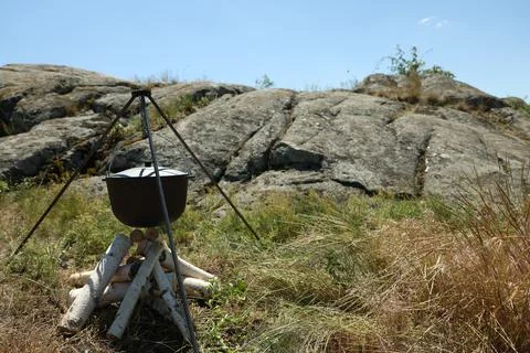 Cauldron above dry firewood arranged for bonfire outdoors. Camping season Stock Photos