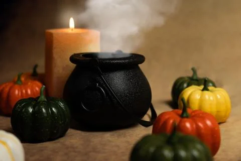 Cauldron with potion inside producing smoke surrounded by candle and pumpkins Stock Photos