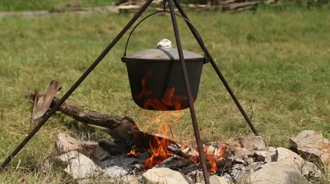 The cauldron on a tripod heated on a campfire Stock Footage 64309312