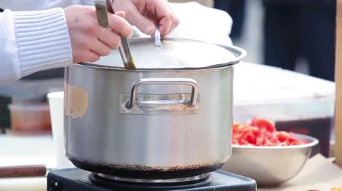 Cauldron with yellow soup cooked over a stove in the street and stirred paddle. Stock Footage 66363753