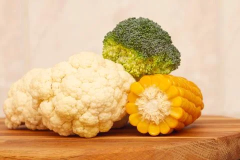 Cauliflower, broccoli cabbage and corn on a wooden board, close-up. Stock Photos