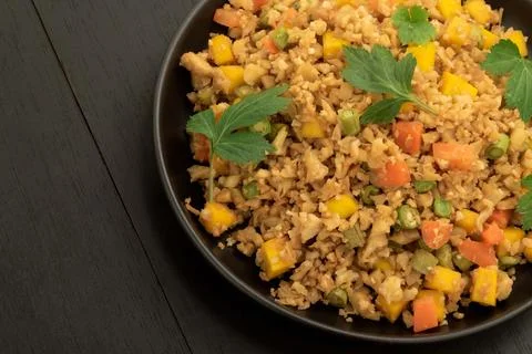 Cauliflower fried rice has vegetable in black dish on wood table. Stock Photos