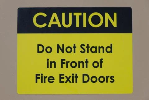 "Caution: Do not stand in front of Fire Exit Doors" warning text and sign Stock Photos