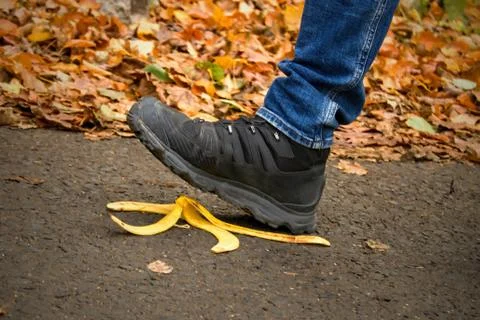 Caution, risk of slipping.The man will slip over the banana peel in a moment. Stock Photos