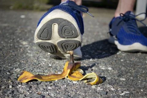 Caution, risk of slipping.The man will slip over the banana peel in a moment. Stock Photos