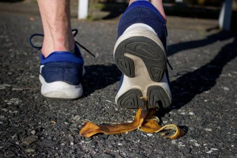 Caution, risk of slipping.The man will slip over the banana peel in a moment. Stock Photos
