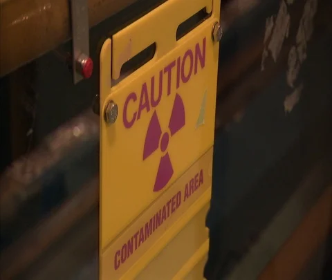 Caution sign and workers in safety gear inside nuclear power station Stock Footage 86692941