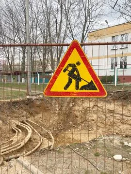 Caution sign indicating construction work ahead, featuring a worker with a Stock Photos