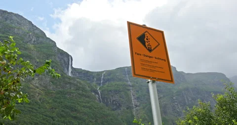 Caution sign by waterfall, warning notice placed near cascading water and rugged Stock-Footage 321085155